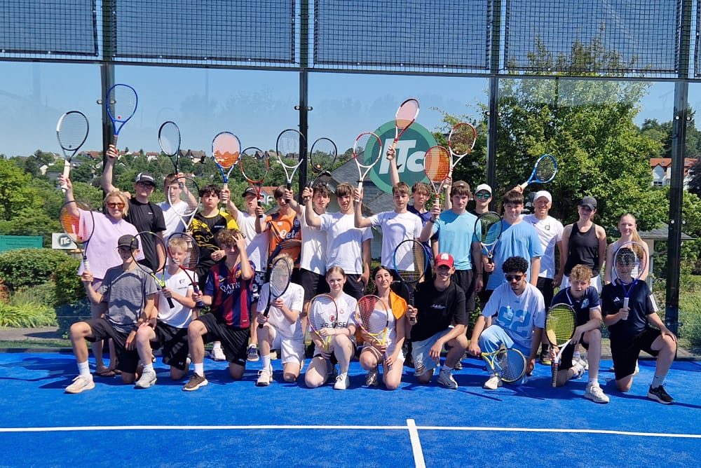 Schülerinnen und Schüler jubeln mit Schlägern auf dem Padelcourt